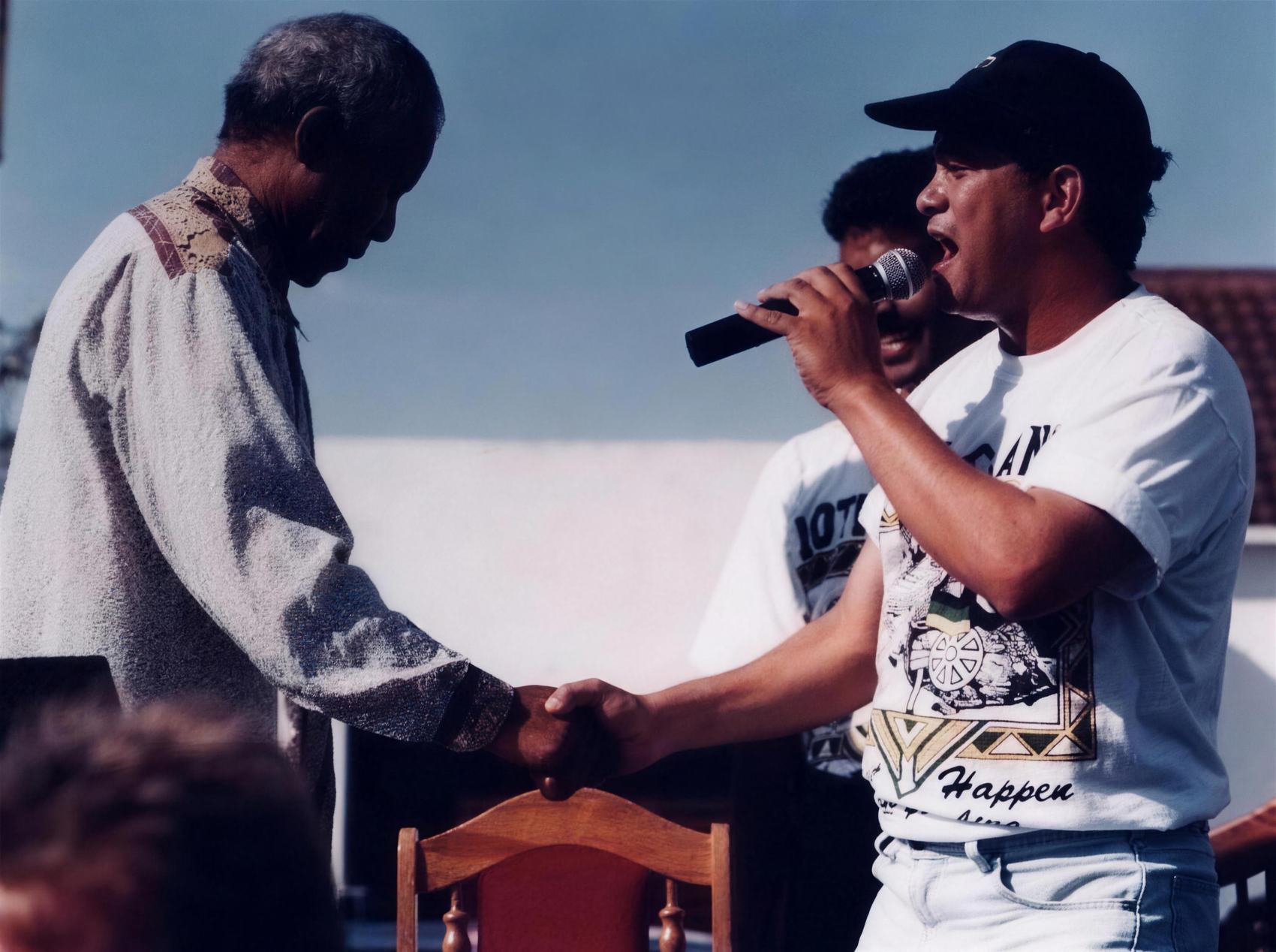 Nelson Mandela bowing his head to take John Pretorius's hand as John sings